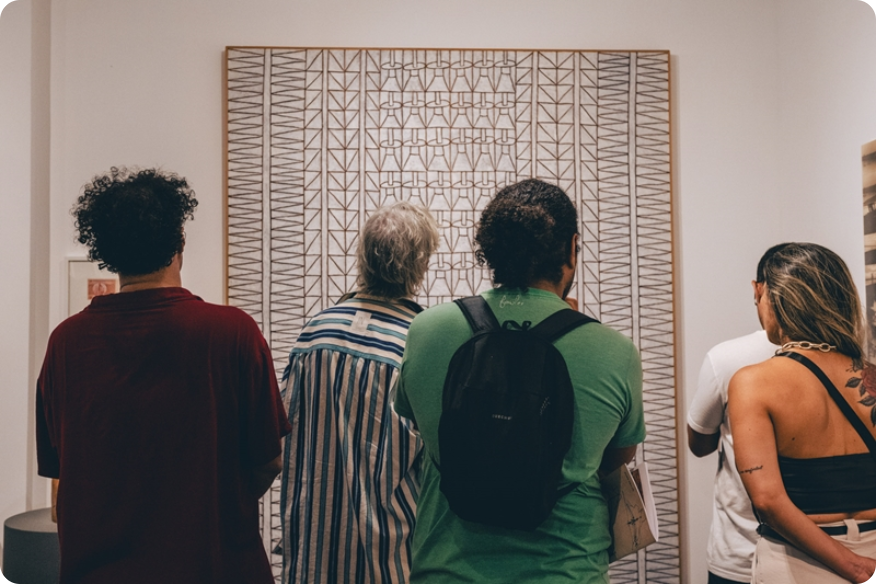 pessoas de costas olhando para quadro na galeria